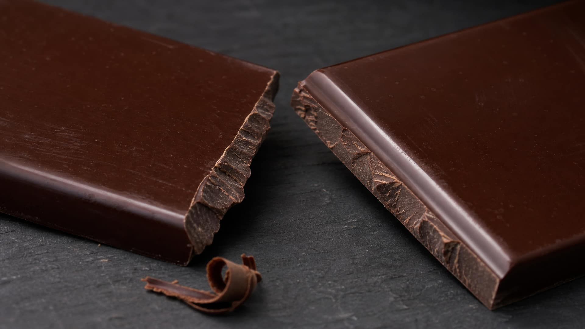 Tempered dark chocolate snapping with a glossy fracture and a clean edge.