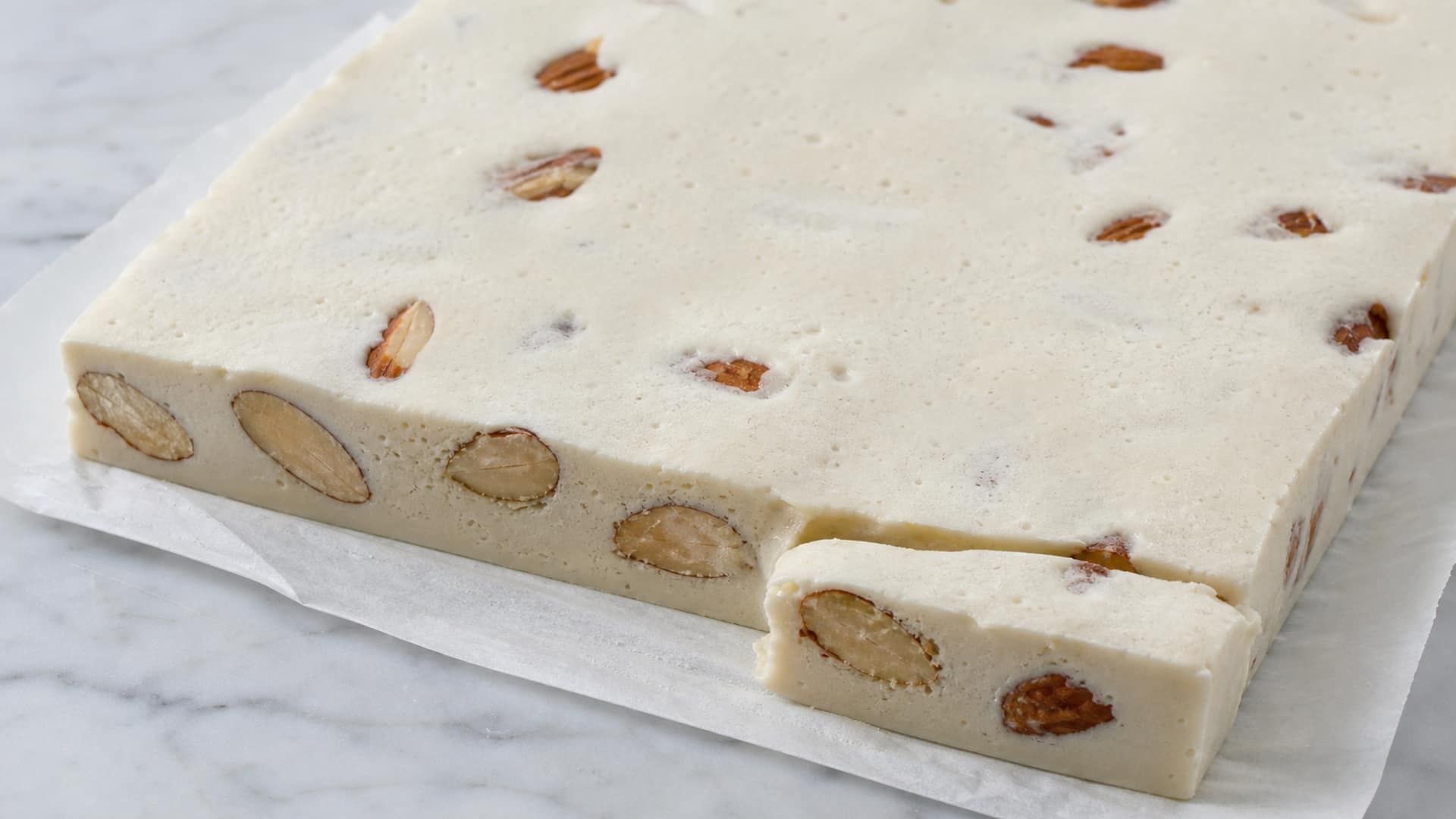 Sticky nougat tearing and stringing as a knife pulls through it.